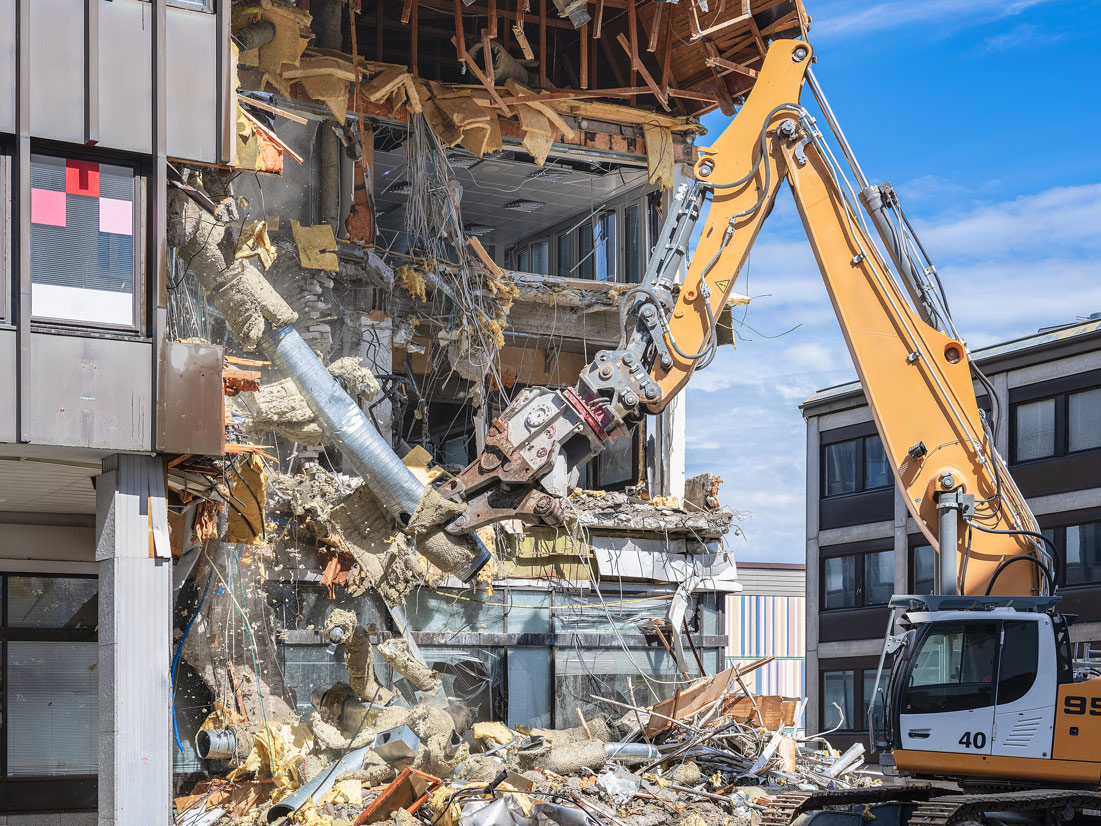 Escavatore con pinza demolitrice durante la demolizione di un edificio