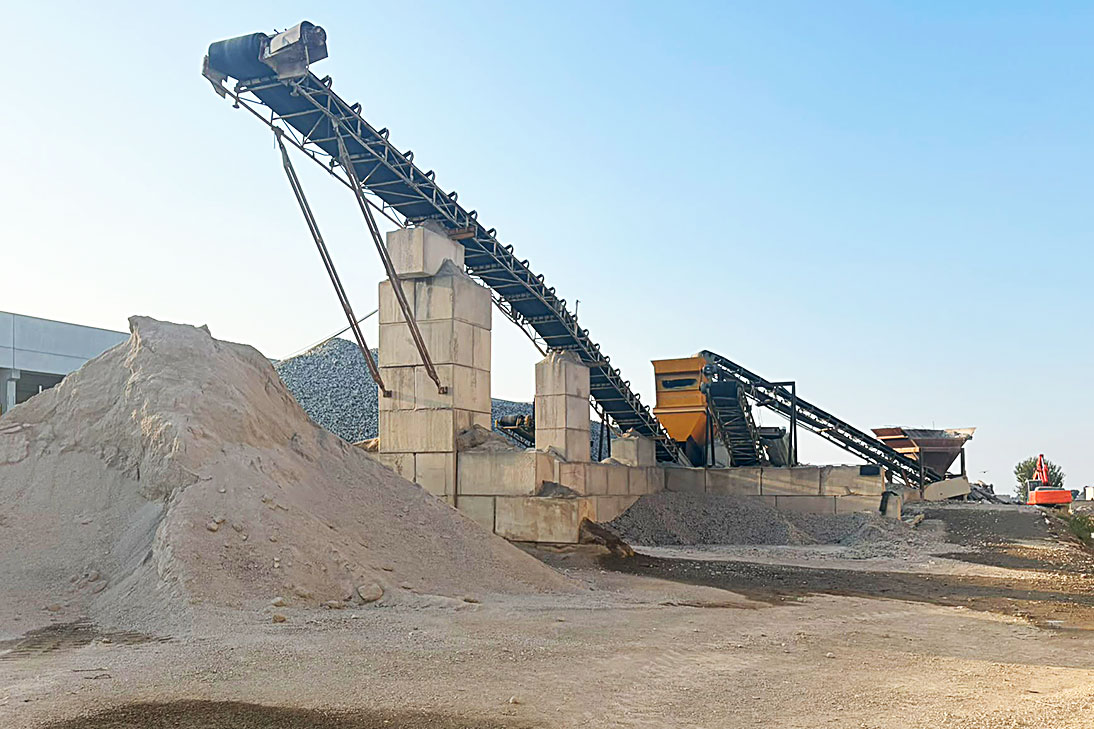 Impianto di frantumazione e vagliatura con nastro trasportatore e cumuli di materiale riciclato