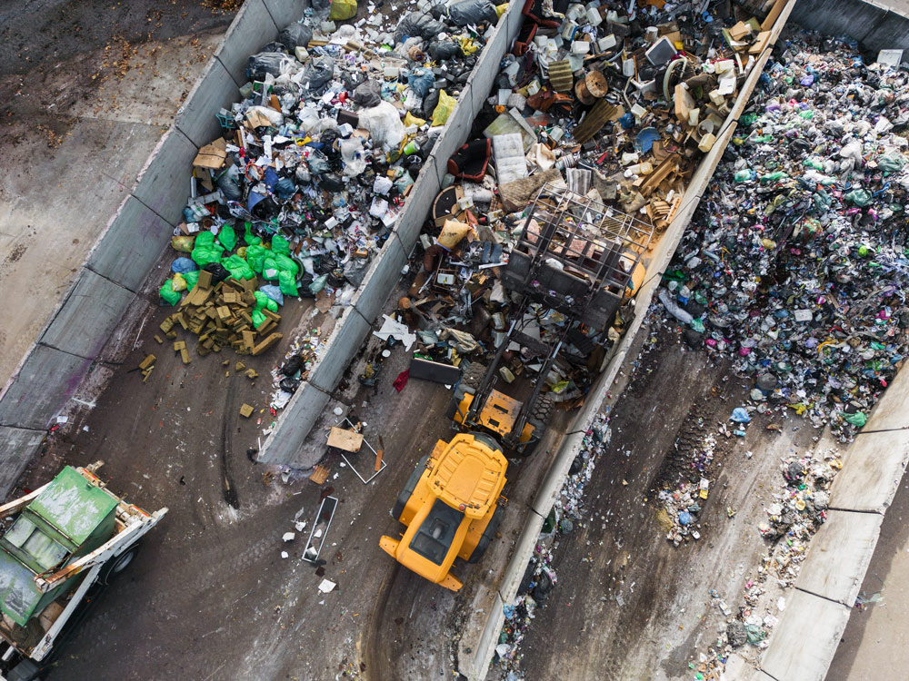 Vista dall'alto di un impianto di selezione rifiuti con pala gommata al lavoro tra i box di stoccaggio
