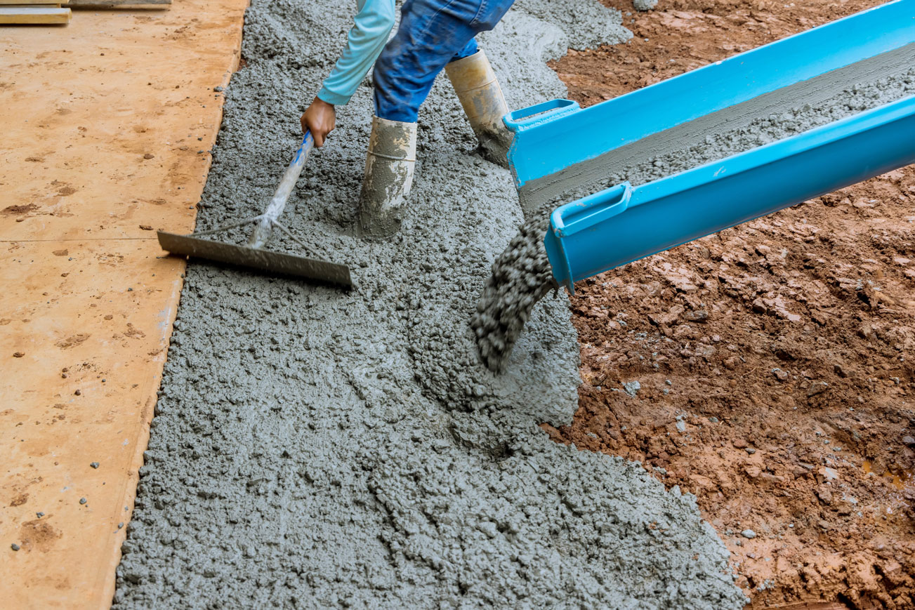 Getto di calcestruzzo fresco livellato da un operaio in cantiere